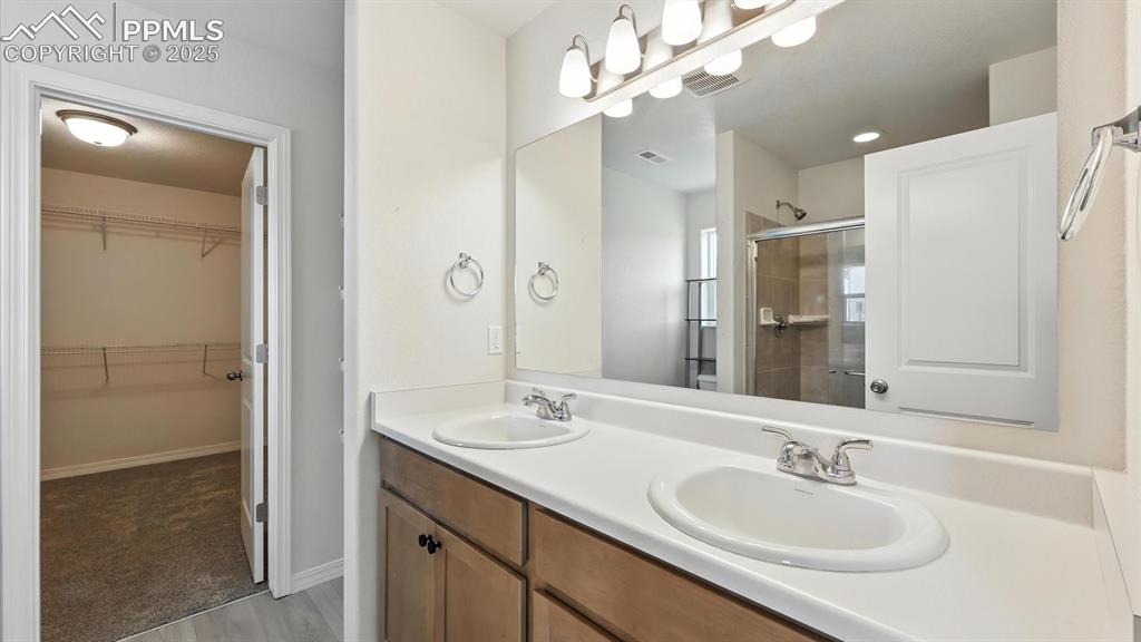 Image 33 of 50: Primary Bathroom with dual sink vanity, tiled shower, and walk in closet.