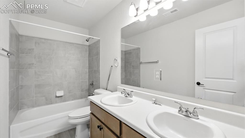 Image 39 of 50: Upper Level Full Hall Bathroom with dual sink vanity, mirror, and tiled tub