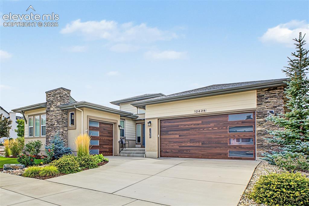 Caption: Beautiful curb appeal with attractive landscaping, a spacious three-car garage, and distinctive cust