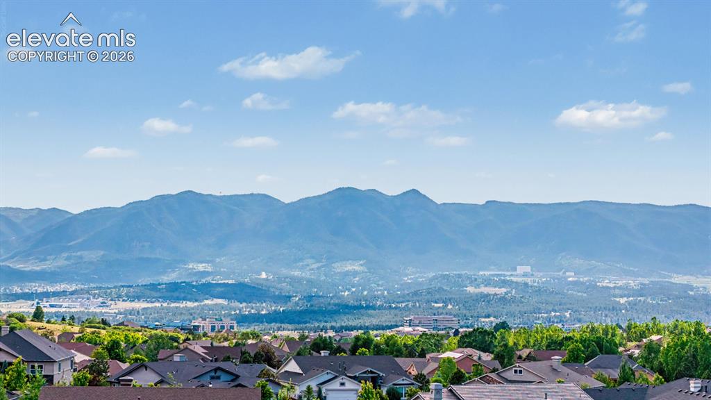 Image 42 of 45: Expansive mountain range backdrop with distant city elements and a resident