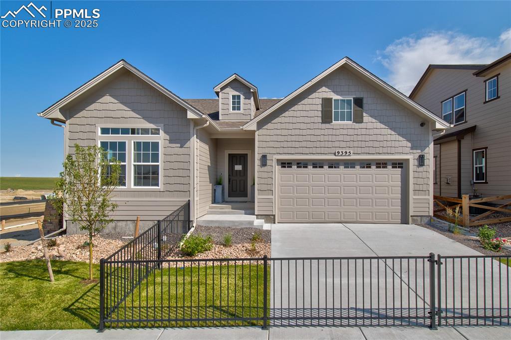 Caption: Craftsman-style house with a fenced front yard, concrete driveway, a garage, a gate, and a shingled 