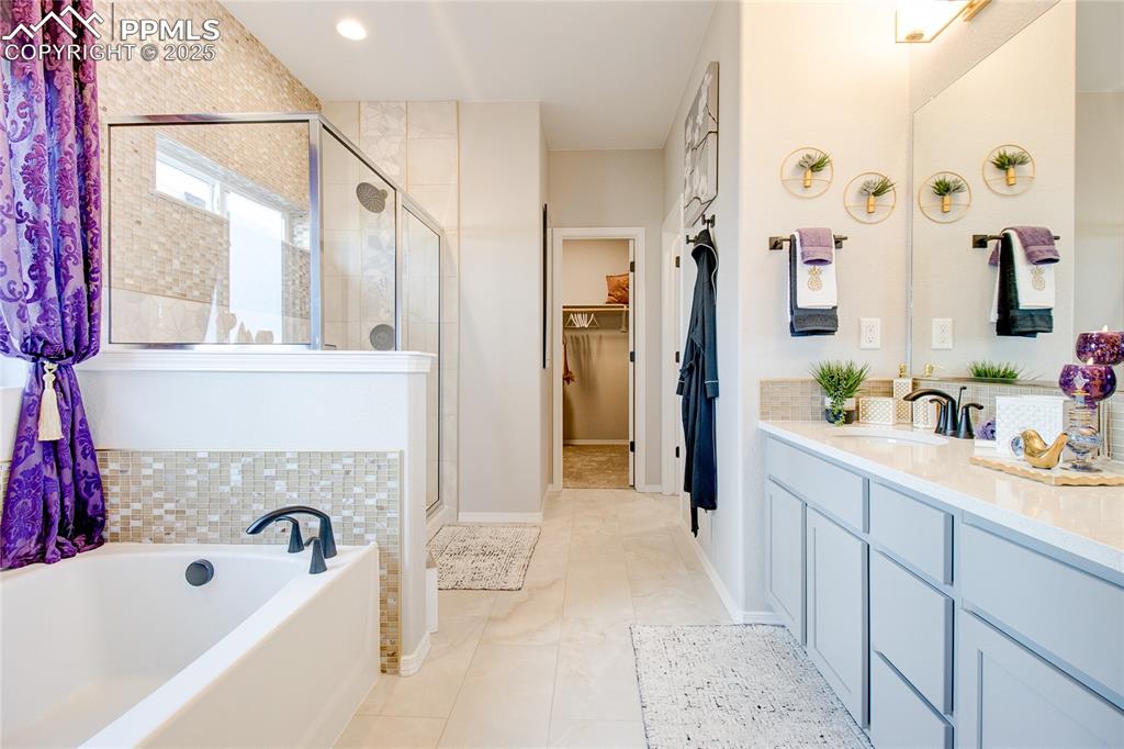 Image 20 of 34: Bathroom featuring a walk in closet, vanity, a shower stall, a garden tub,