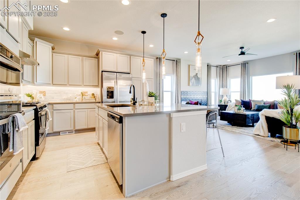 Image 9 of 34: Kitchen featuring backsplash, a kitchen island with sink, stainless steel a