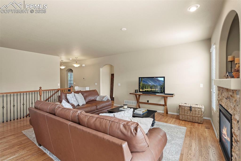 Image 11 of 44: Living room featuring arched walkways, light wood-type flooring, a glass co
