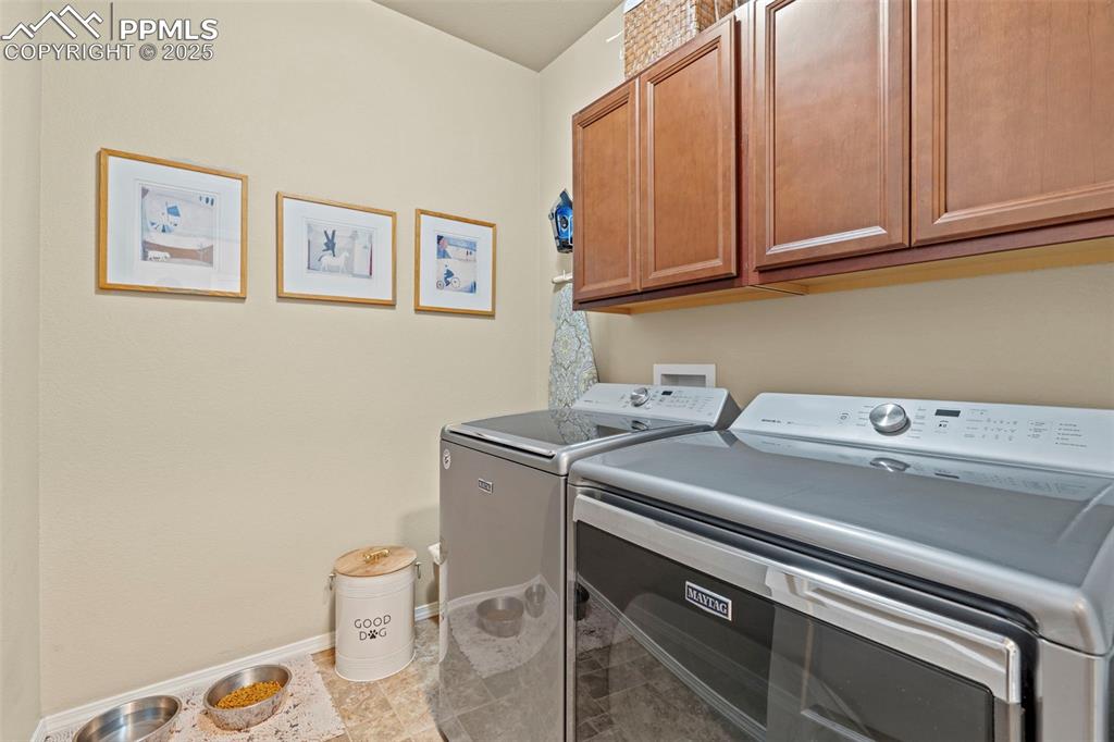 Image 19 of 44: Laundry area featuring independent washer and dryer, cabinet space, and bas