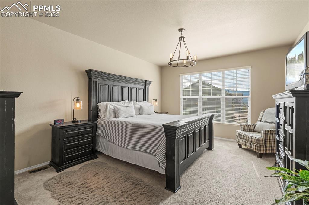 Image 23 of 44: Carpeted bedroom with baseboards and a chandelier