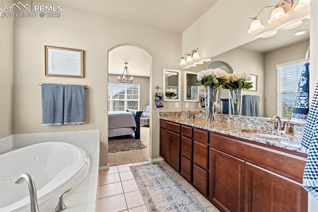 Image 29 of 44: Bathroom with double vanity, a bath, tile patterned flooring, ensuite bath,