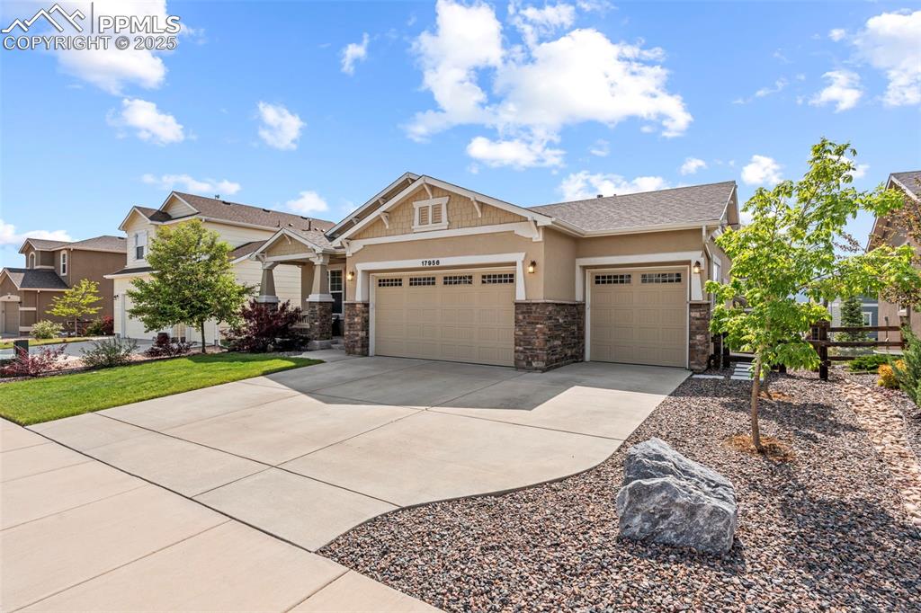 Image 3 of 44: Craftsman-style home with an attached garage, driveway, stone siding, and s