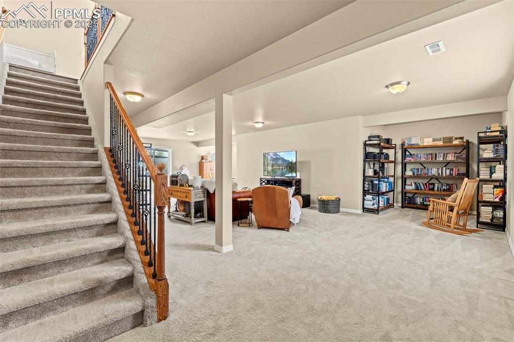 Image 33 of 44: Carpeted living room featuring stairs and baseboards