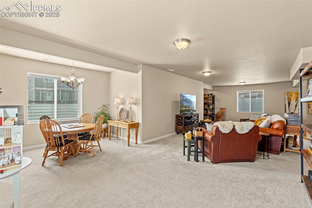 Image 35 of 44: Carpeted living area with a chandelier and baseboards