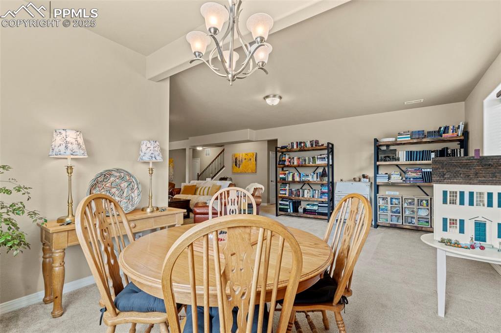 Image 36 of 44: Carpeted dining room with a chandelier, stairs, and baseboards