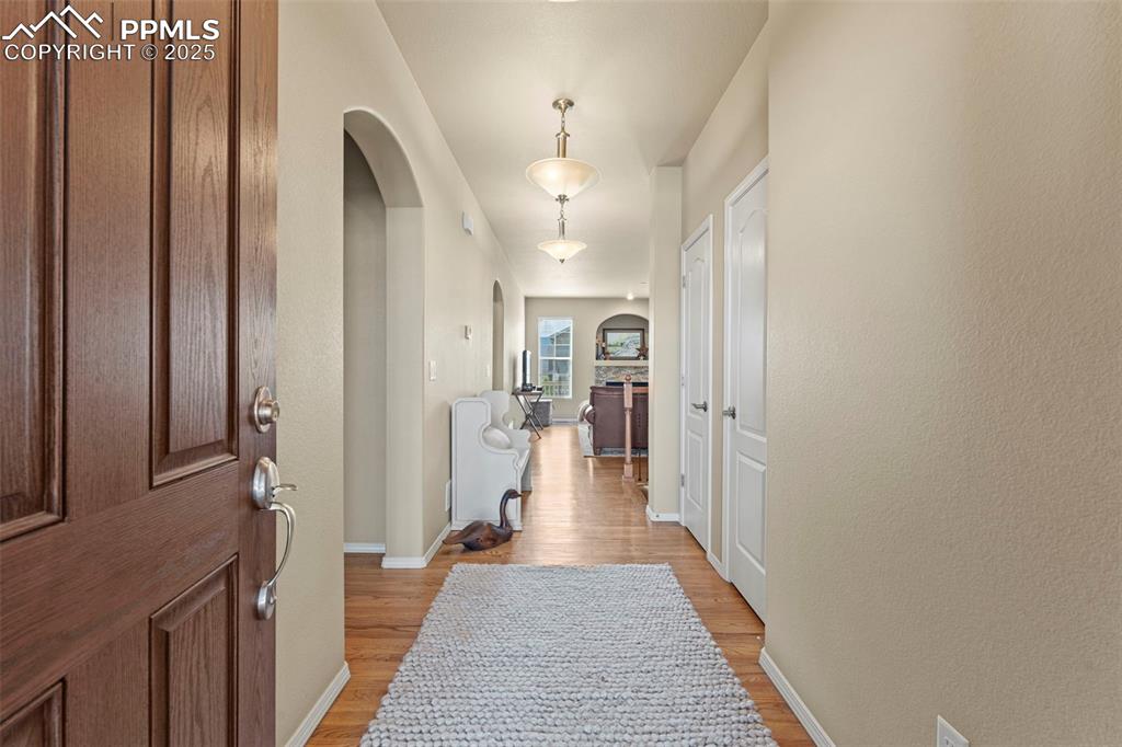 Image 6 of 44: Foyer with arched walkways, light wood finished floors, and baseboards