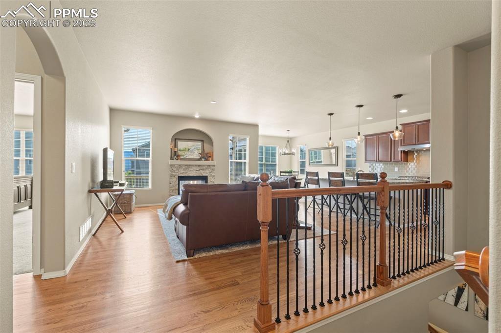 Image 8 of 44: Living room featuring light wood finished floors, a fireplace, arched walkw