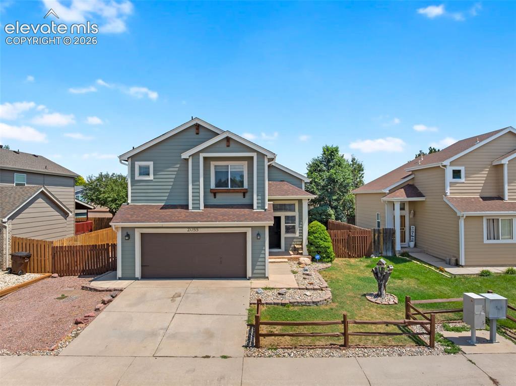 Caption: Two-story residence with a two-car garage, concrete driveway, and a fenced yard