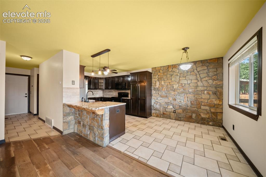 Image 10 of 48: Stone accent wall, wood-finish flooring, tiled flooring, dark wood cabinetr