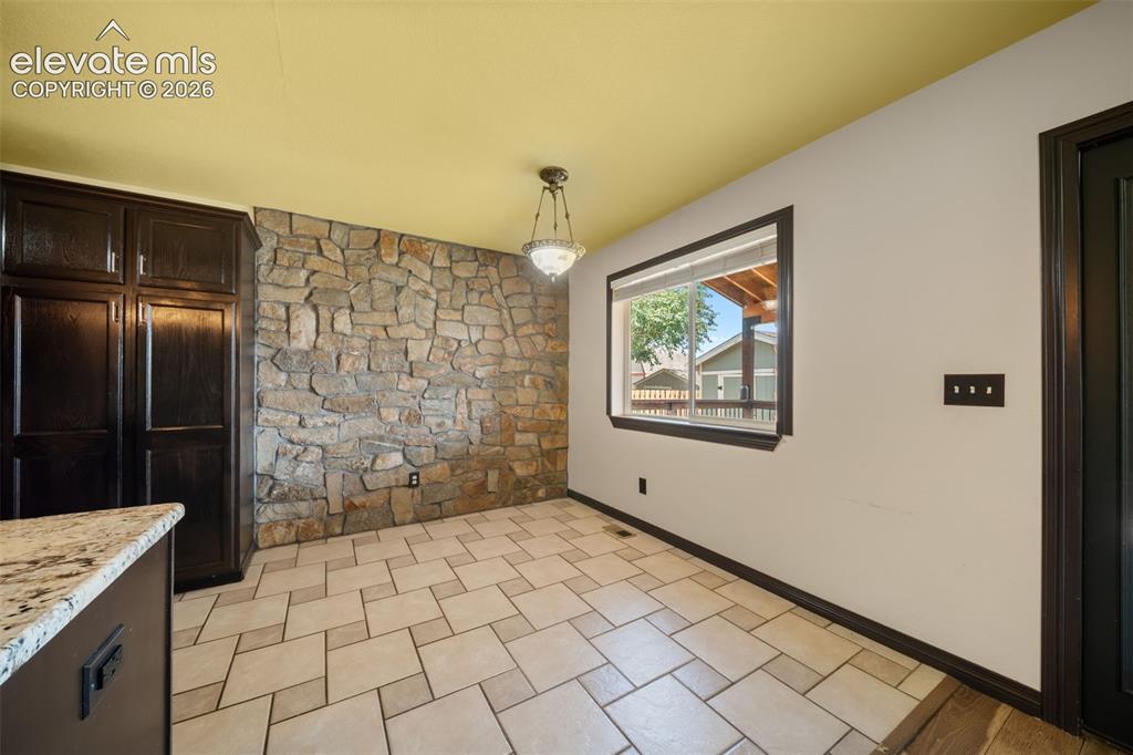 Image 11 of 48: Stone accent wall, tiled flooring, built-in cabinetry, window with exterior