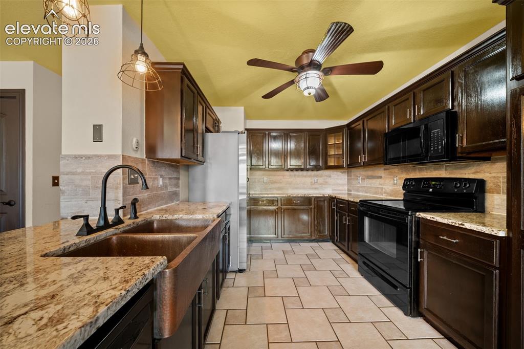 Image 12 of 48: Kitchen featuring granite countertops, a copper farmhouse sink, dark wood c