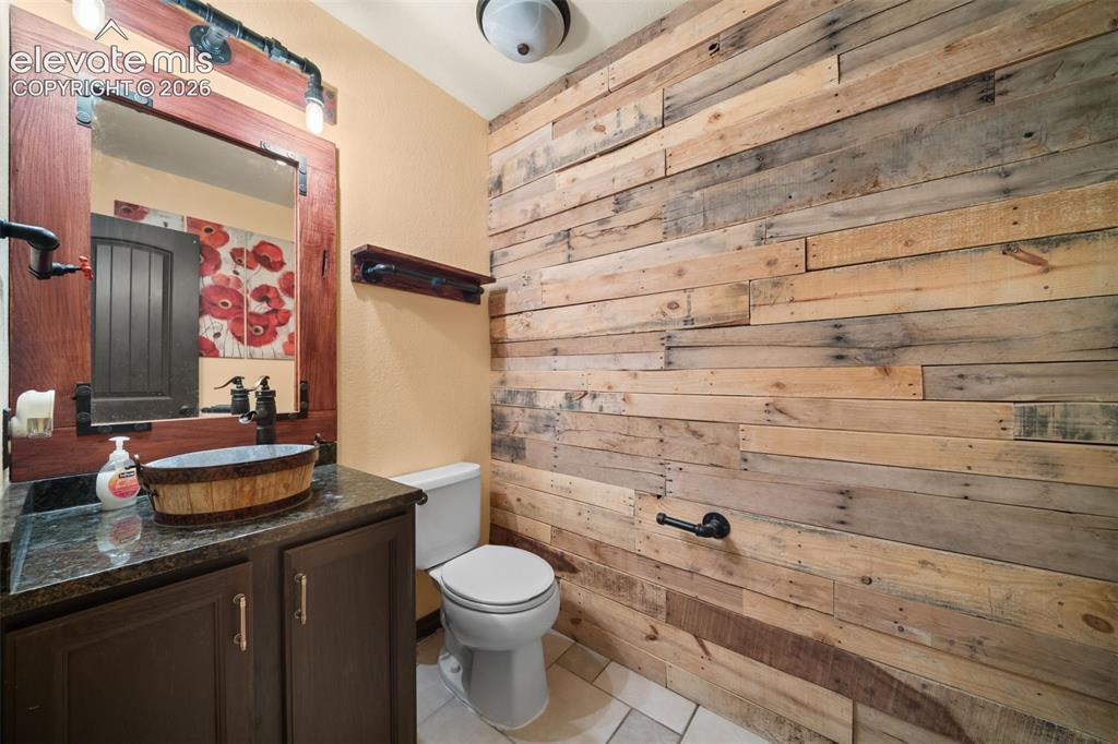 Image 14 of 48: Wood-paneled accent wall, dark wood vanity with cabinet storage, vessel sin