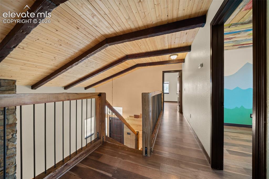 Image 16 of 48: Wood-finish flooring throughout, exposed wood beam ceiling, and a wood and 