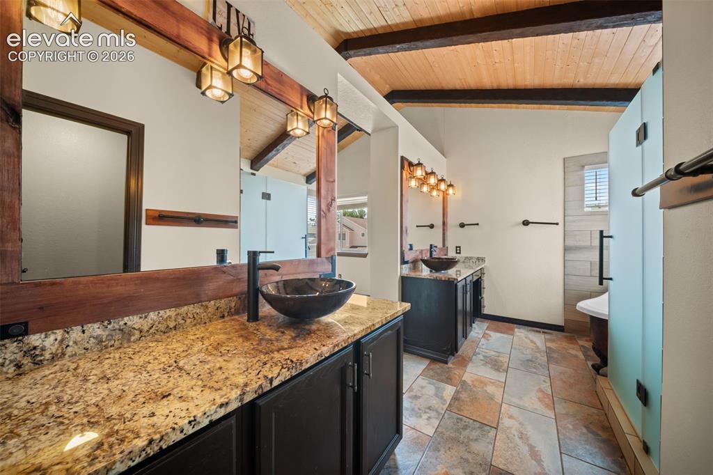 Image 19 of 48: Vaulted wood-plank ceiling with exposed beams, dual vanity with granite cou