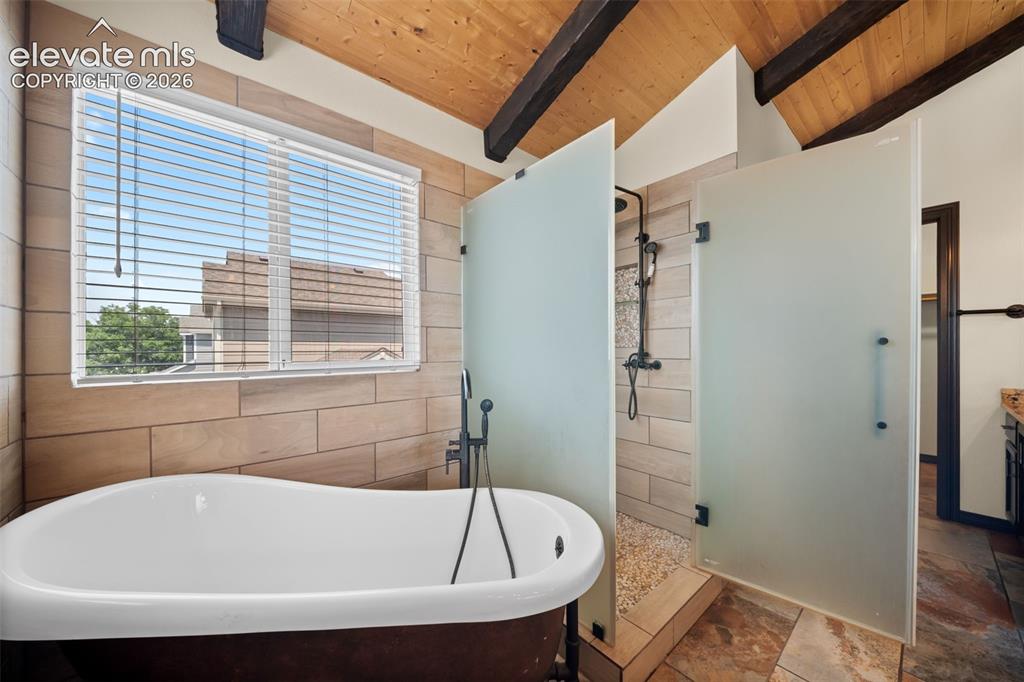 Image 21 of 48: Vaulted wood-plank ceiling with exposed beams, freestanding soaking tub wit