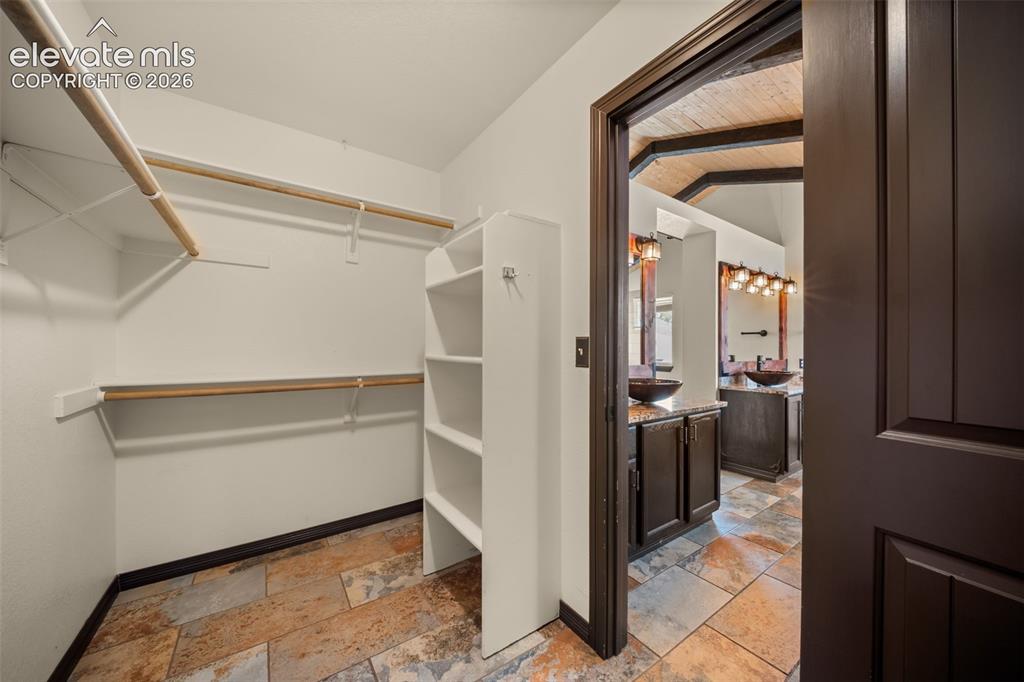 Image 22 of 48: Walk-in closet with multi-level hanging rods and built-in shelving