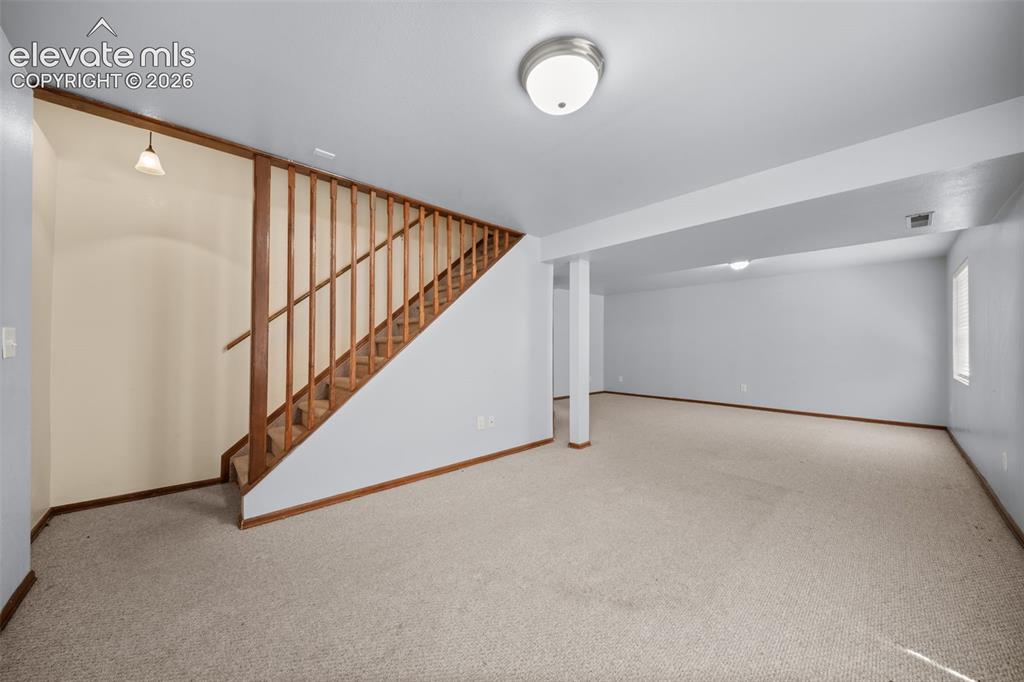 Image 29 of 48: Expansive open-concept room with neutral carpeting, recessed ceiling lighti