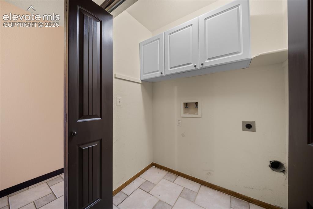 Image 35 of 48: White shaker-style cabinetry, a built-in shelving unit, and tile flooring