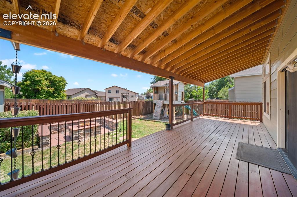 Image 37 of 48: Expansive wooden deck with an exposed beam ceiling, black wrought iron rail
