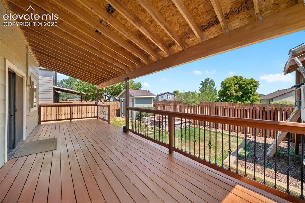 Image 39 of 48: Spacious covered deck featuring wood-finish flooring, a wood railing with b