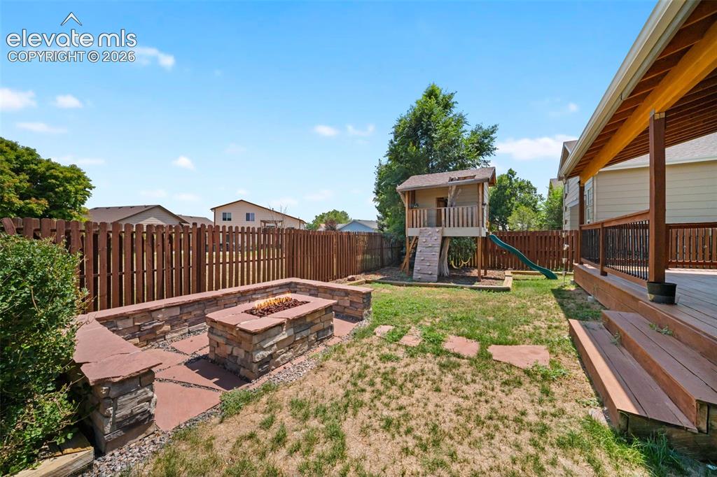 Image 40 of 48: Expansive backyard featuring a built-in stone fire pit, wood privacy fencin