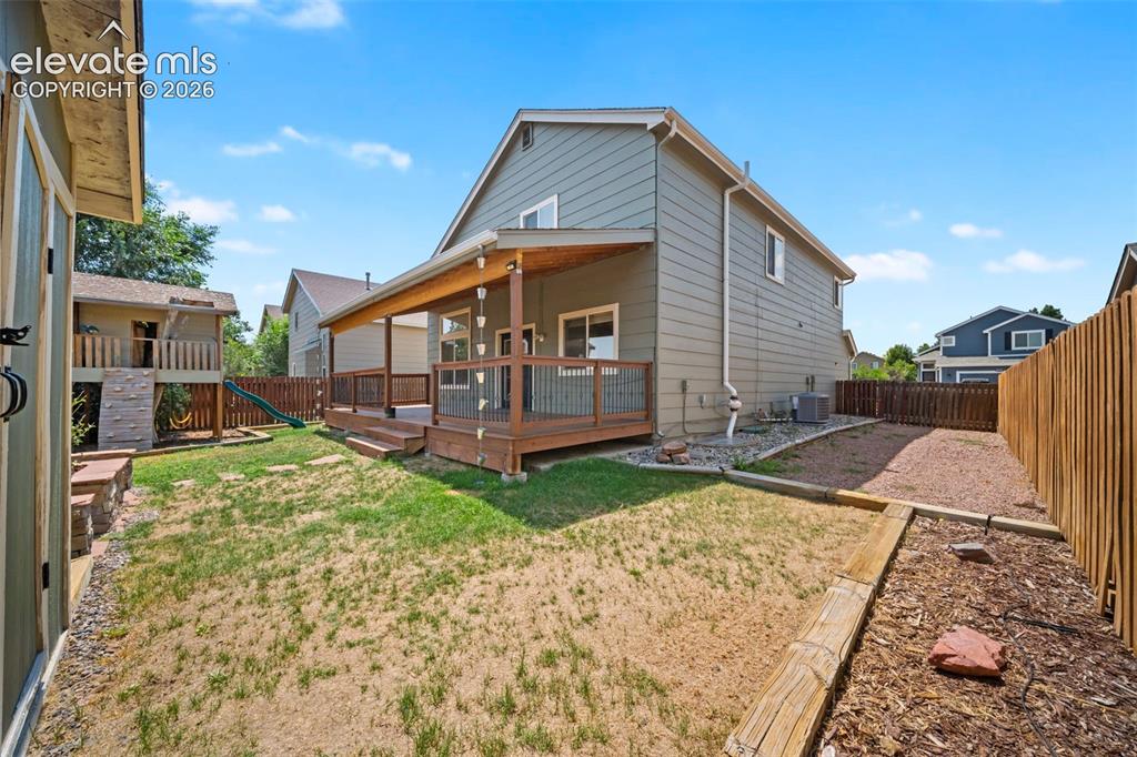 Image 42 of 48: Expansive backyard featuring a covered deck, wood privacy fence, and a stor