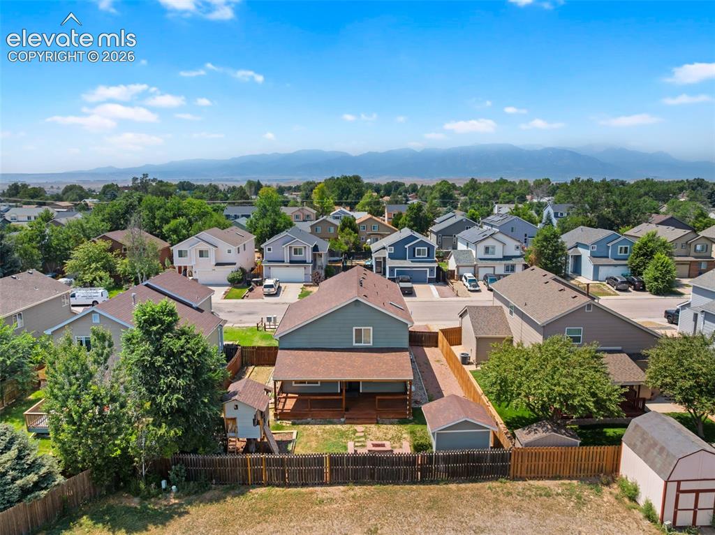 Image 48 of 48: Expansive fenced backyard with a wood deck, built-in fire pit, and detached