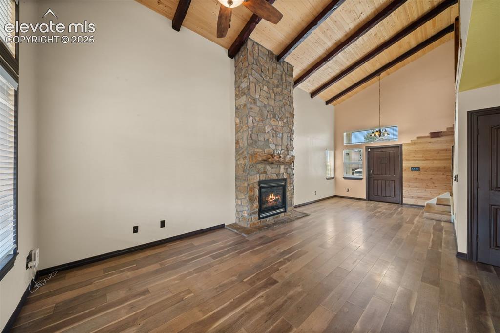 Image 5 of 48: Vaulted ceiling with exposed wood beams, stone-clad fireplace, wood-finish 