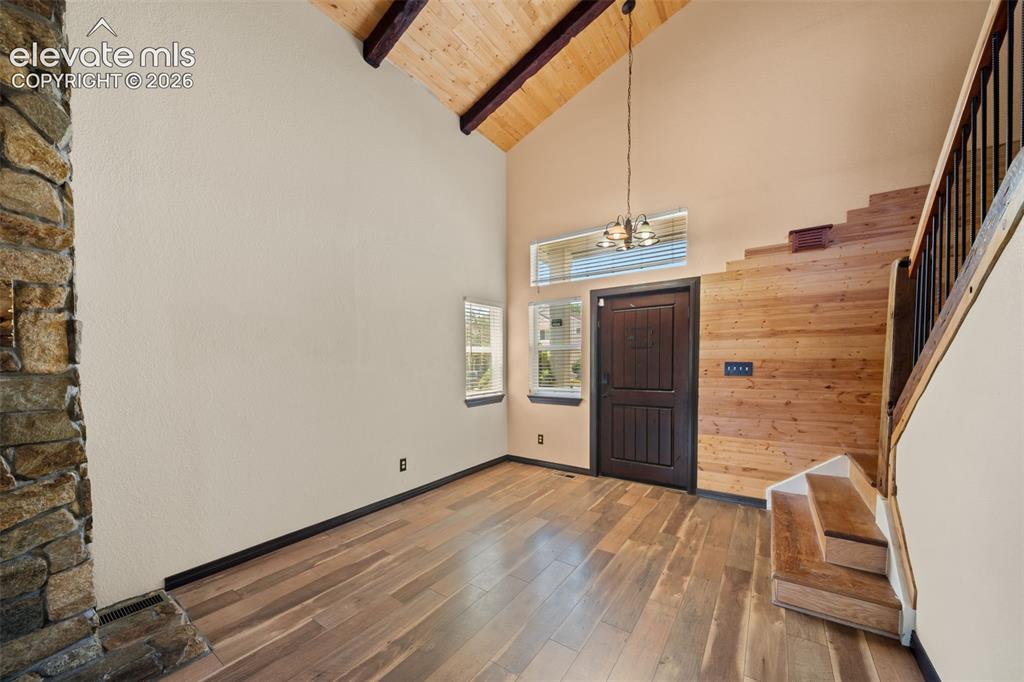 Image 6 of 48: Vaulted wood plank ceiling with exposed beams, stone-clad fireplace, wood-f