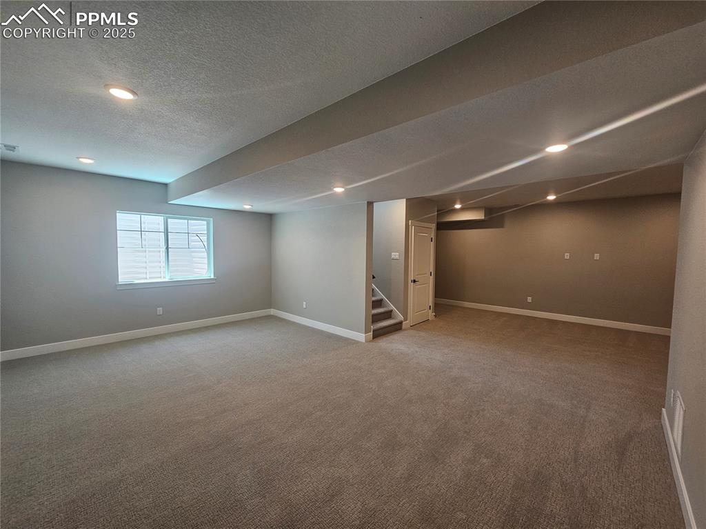 Image 14 of 15: Basement featuring carpet, stairs, a textured ceiling, and recessed lightin