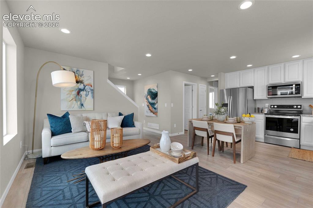 Image 11 of 31: Open-concept living area featuring light wood-finish flooring, recessed lig