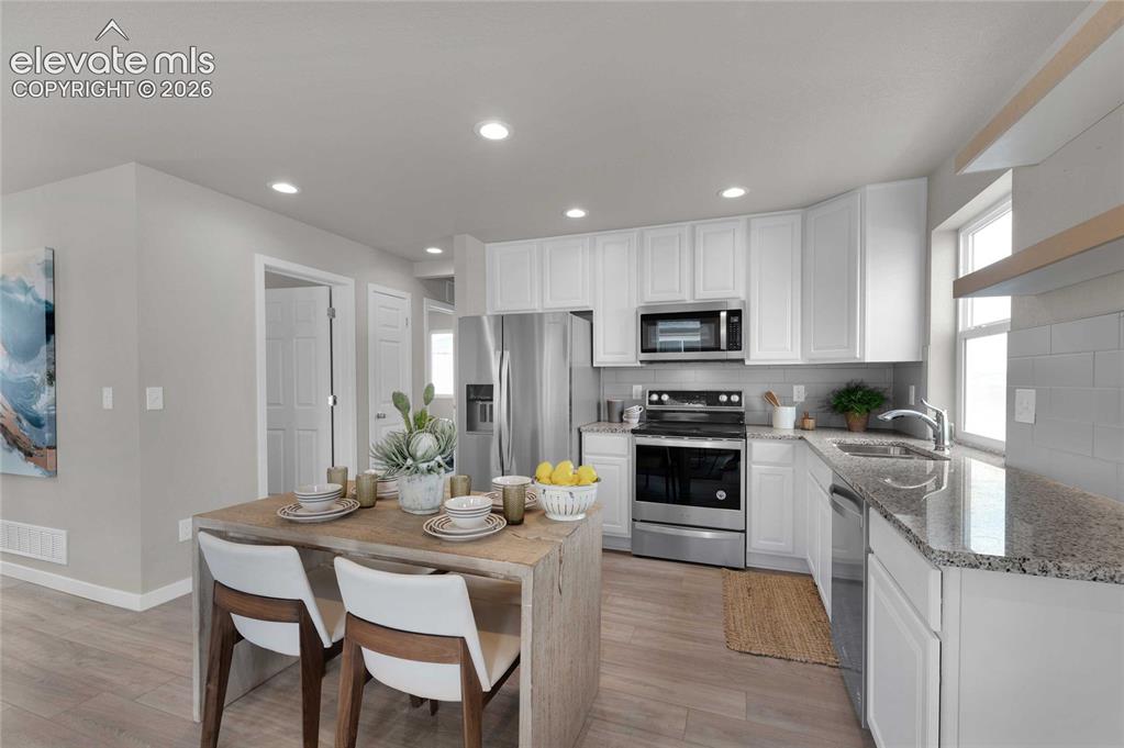 Image 14 of 31: Kitchen featuring white shaker cabinetry, stainless steel appliances, grani
