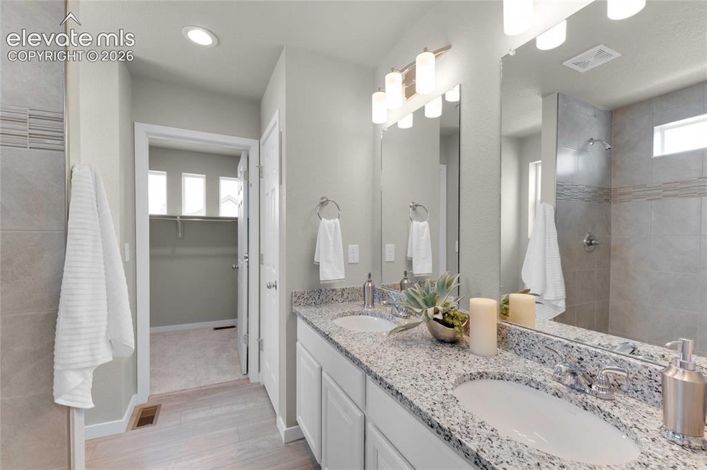 Image 20 of 31: Bathroom featuring a double vanity with stone countertops, white cabinetry,