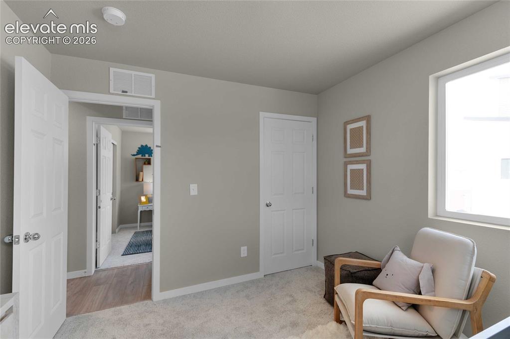 Image 25 of 31: Carpeted room featuring a white paneled door, a single-pane window, and lig