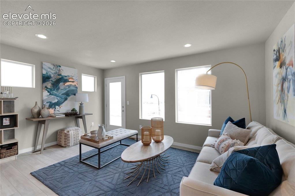Image 8 of 31: Light-filled living area featuring wood-finish flooring, recessed lighting,
