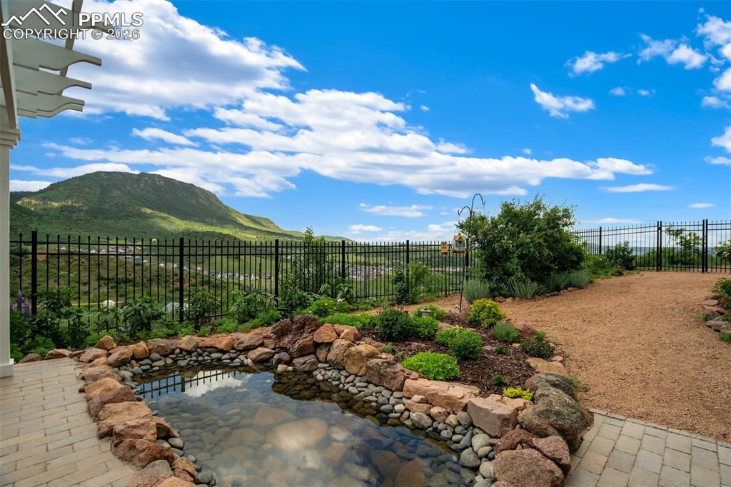 Image 31 of 40: Fully landscaped back yard with stone patio, pergola, and pond