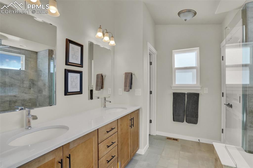 Image 22 of 42: Large primary suite bathroom with double vanity, extended shower, separate