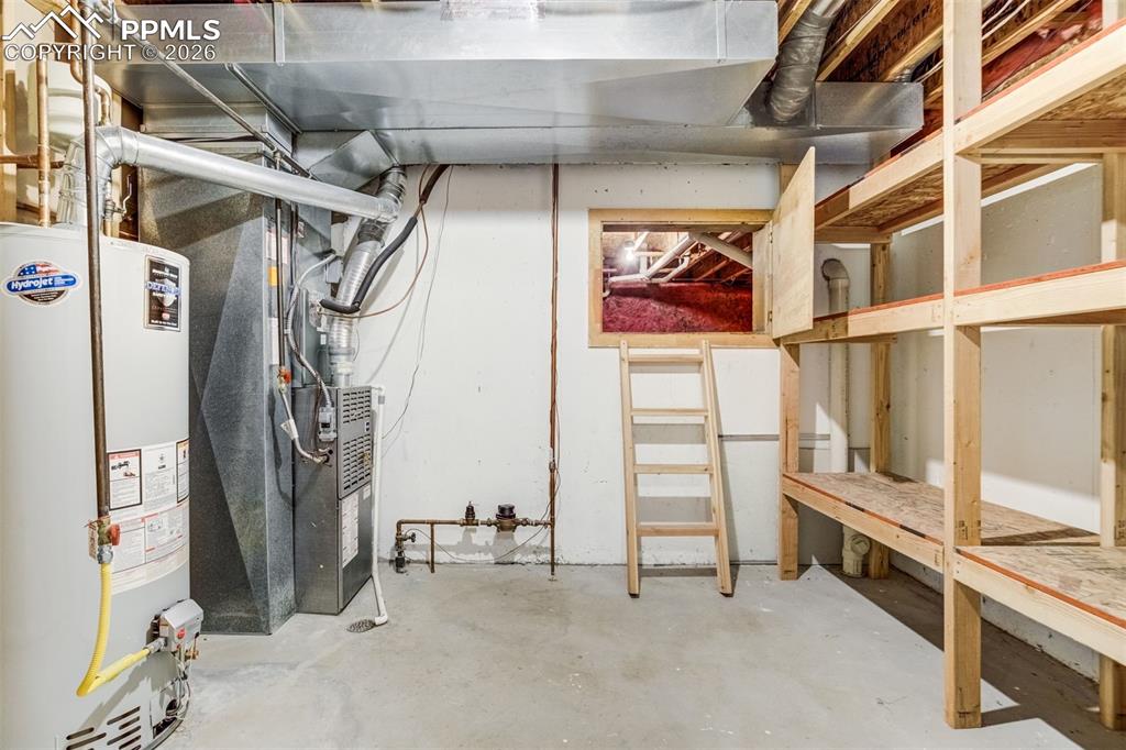 Image 34 of 43: Mechanical room with shelving opens to crawlspace