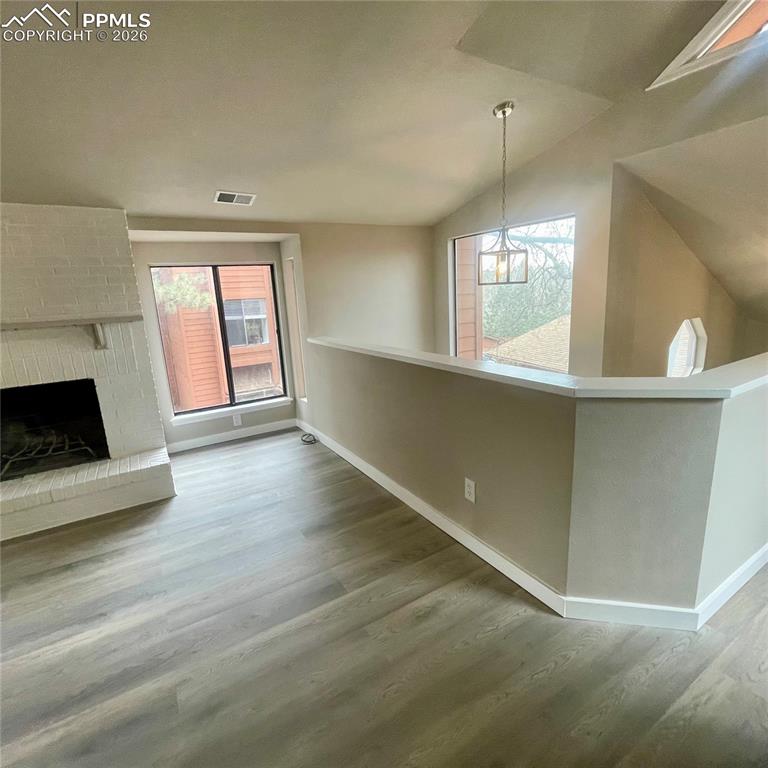 Image 14 of 43: Great Room featuring new flooring, a brick fireplace & lofted ceiling