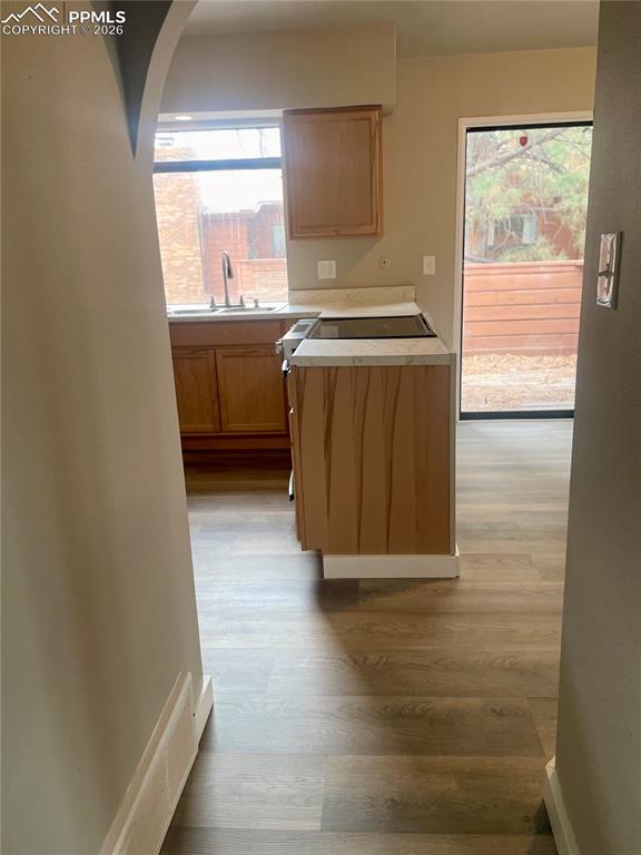 Image 30 of 43: Kitchen featuring light countertops, arched walkways, and light wood-style