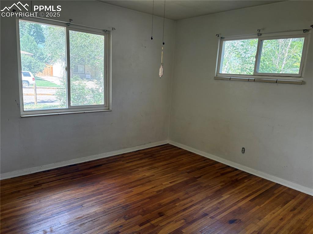 Image 11 of 11: Unfurnished room with dark wood-type flooring and baseboards