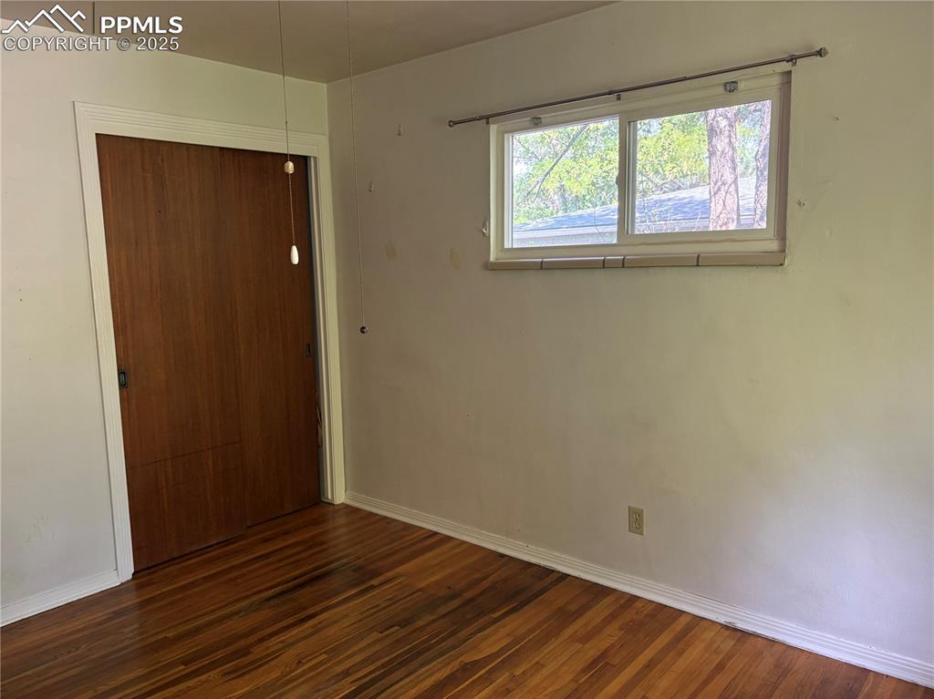 Image 7 of 11: Unfurnished room with baseboards and dark wood-style flooring