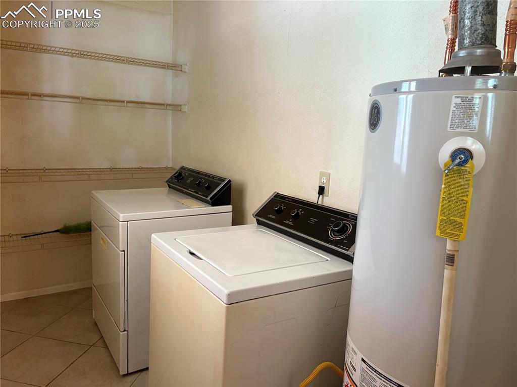 Image 9 of 11: Laundry room with water heater, light tile patterned floors, and separate w