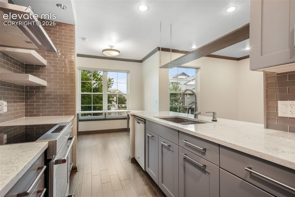 Image 16 of 50: Kitchen featuring light-toned stone-finish countertops, grey cabinetry with